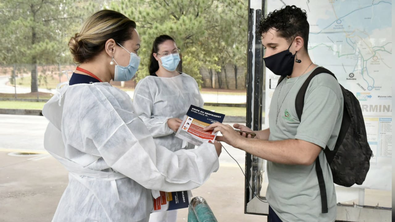 Profissionais da saúde entregando folheto a passageiro do terminal CECAP em Jundiaí