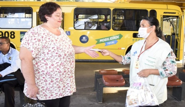 Foto de distribuição de máscara em terminal de ônibus urbano