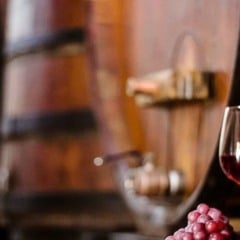 Taça de vinho tinto e uvas em adega com barris de madeira em Jundiaí. Taça de vinho tinto e uvas em adega com barris de madeira em Jundiaí.