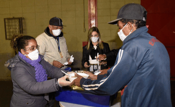 Equipe serve alimentação a pessoas em situação de rua