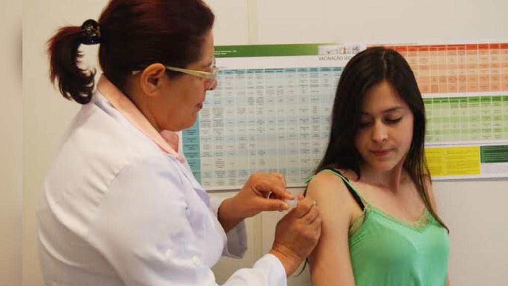 Profissional da saúde aplicando vacina em mulher