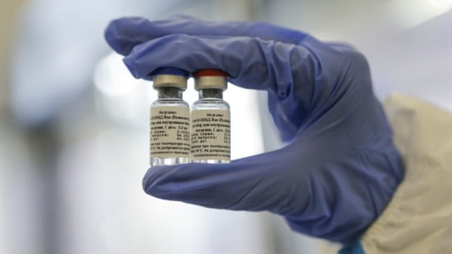 Pessoa segurante duas ampolas da vacina russa, Sputnik V.