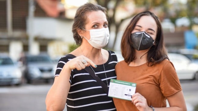 Mulher e menina com cartão de vacinação