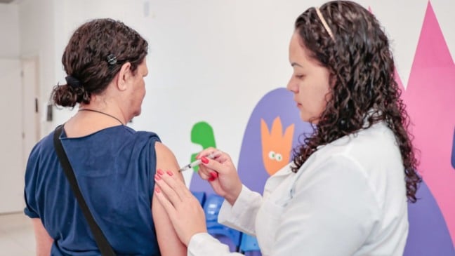 Enfermeira aplicando vacina em paciente.