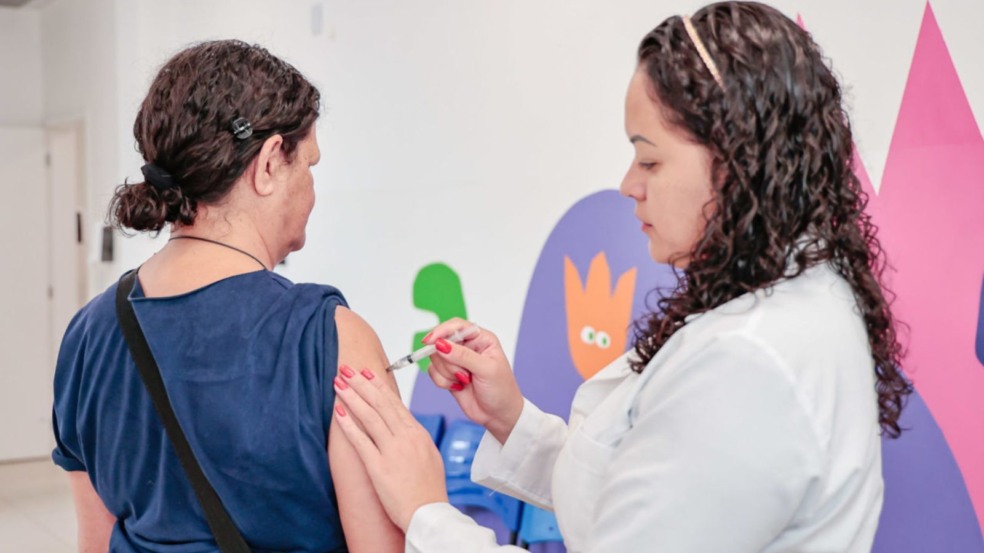 Enfermeira aplicando vacina em paciente.
