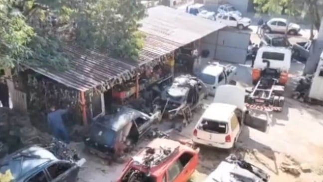 Desmanche de veículos em uma área aberta em Várzea Paulista, com várias carcaças de carros e peças espalhadas pelo terreno.