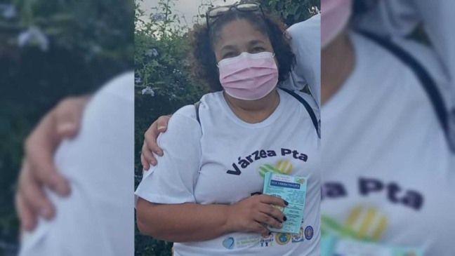 Mulher com uma camisa branca divulgando seu trabalho voluntario