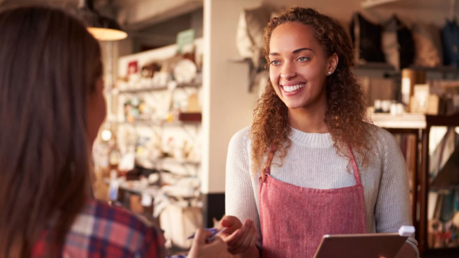 Mulher vendendo item para outra mulher.