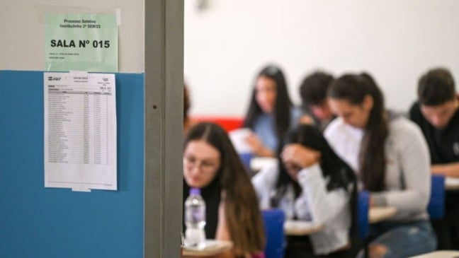 Alunos sentados em carteiras fazem a prova do Vestibulinho das Etecs, com lista de presença e identificação da sala fixadas na porta.