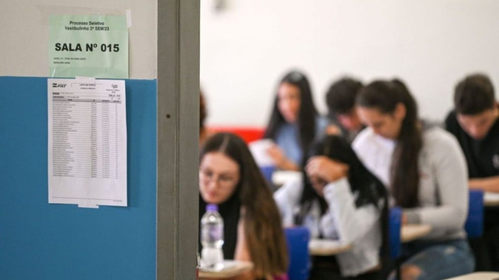 Alunos sentados em carteiras fazem a prova do Vestibulinho das Etecs, com lista de presença e identificação da sala fixadas na porta.
