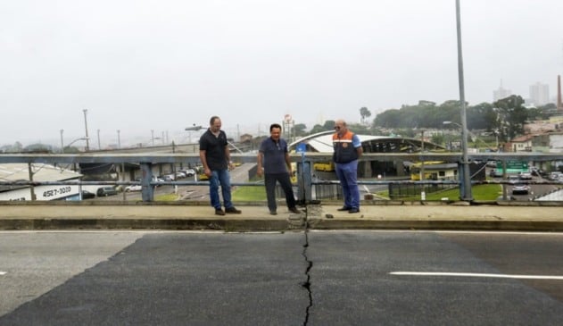 Homens sobre viaduto com rachadura no asfalto