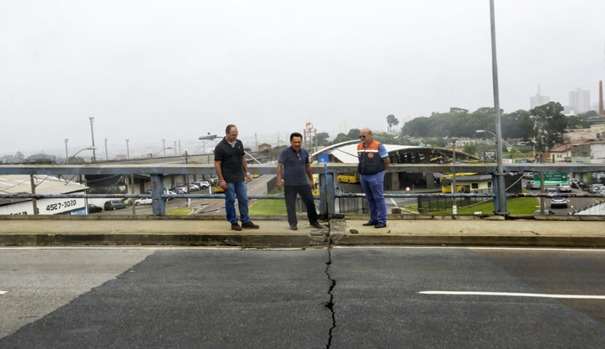 Homens sobre viaduto com rachadura no asfalto
