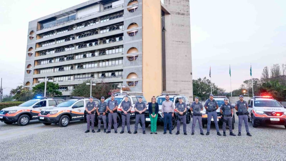 Policiais militares, prefeito Gustavo Martinelli e vereadora Carla Basílio posam em frente a viaturas novas da Polícia Militar, estacionadas em frente ao Paço Municipal de Jundiaí.