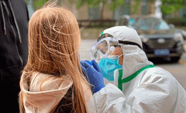 Criança é testada por pessoas com equipamentos de segurança