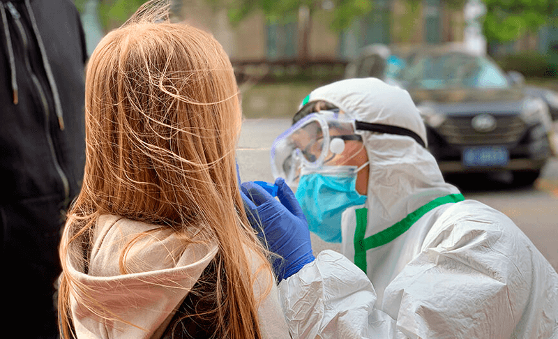Criança é testada por pessoas com equipamentos de segurança