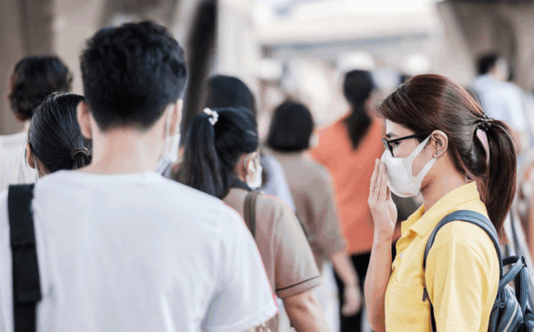 Mulher com máscara caminha com aglomeração