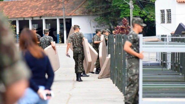Soldados carregam camas e colchões