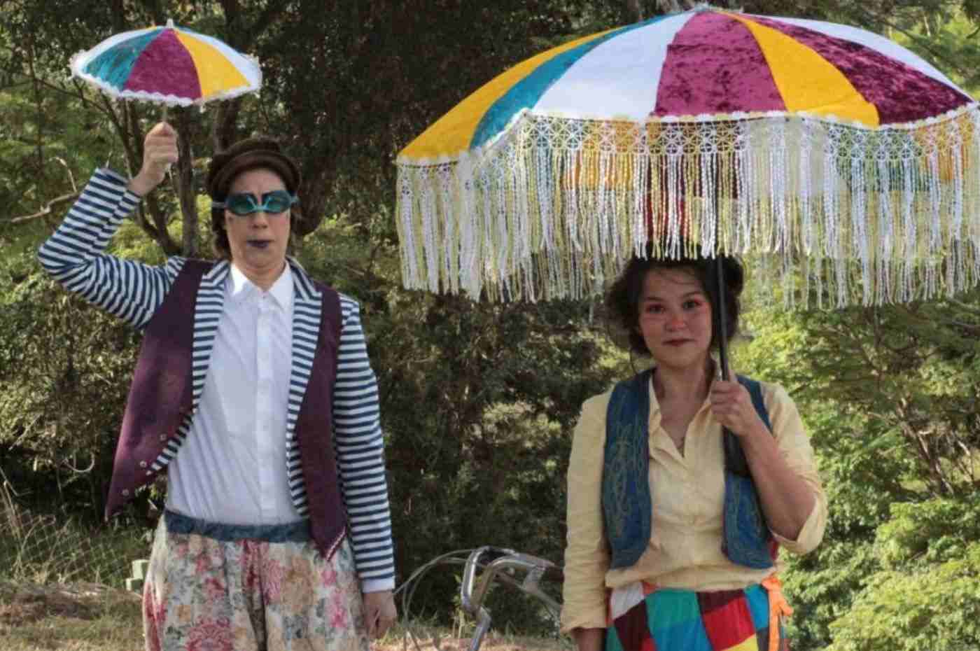 Atrizes do espetáculo Circo da Luz na Fábrica das Infâncias Japy, segurando guarda-sóis coloridos em apresentação ao ar livre.