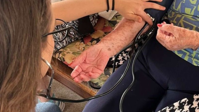 Estudante aferindo pressão de idosos na Faculdade de Medicina de Jundiaí.