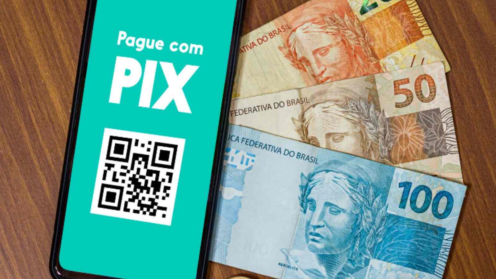 Aparelho celular com tela no PIX e notas de dinheiro ao lado.