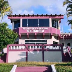 Fachada da Prefeitura Municipal de Jarinu com letreiro visível e vegetação ao redor em dia ensolarado.
