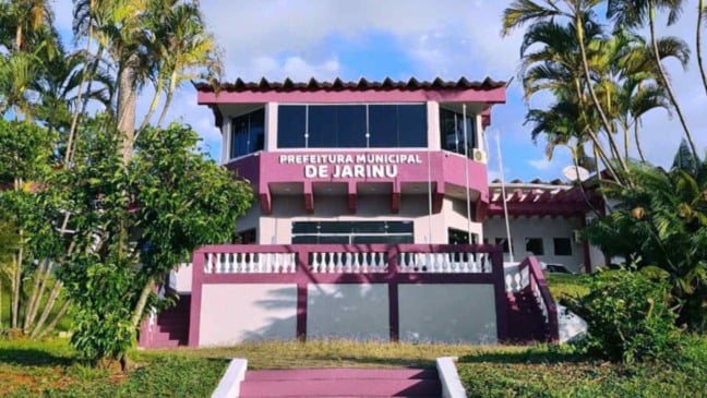 Fachada da Prefeitura Municipal de Jarinu com letreiro visível e vegetação ao redor em dia ensolarado.