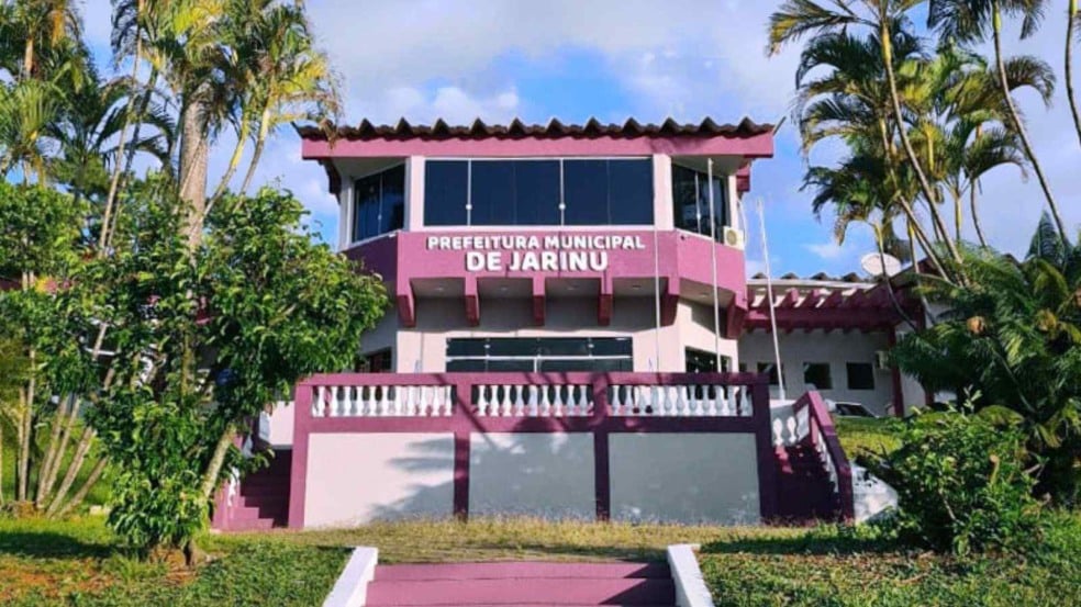 Fachada da Prefeitura Municipal de Jarinu com letreiro visível e vegetação ao redor em dia ensolarado.