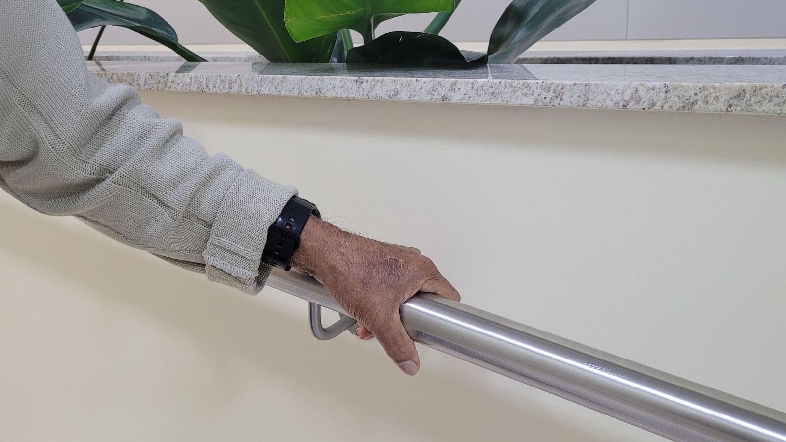Pessoa idosa segurando em um corrimão