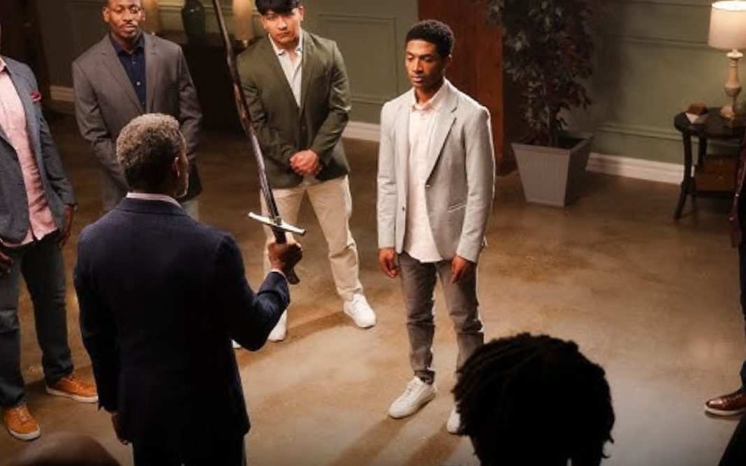 Cena do filme "A Forja" com personagem segurando espada diante de jovens em pé, simbolizando um momento de ensinamento e liderança.