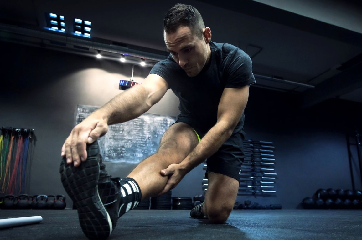 Homem em academia fazendo alongamento Homem em academia fazendo alongamento