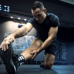 Homem em academia fazendo alongamento