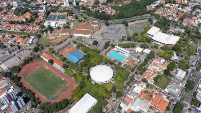 Vista aérea do Complexo Esportivo Bolão em Jundiaí, com ginásio central, pista de atletismo, piscina olímpica e quadras esportivas cercadas por área urbana.