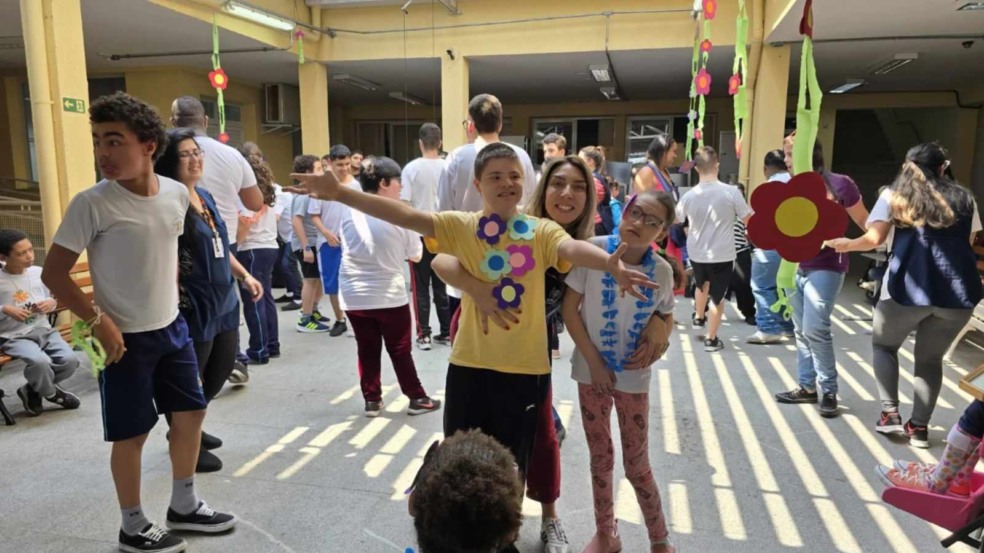 APAE Jundiaí realiza baile da primavera para alunos; jovens se divertem com professores em meio às flores.