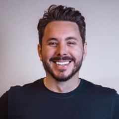 Alan Barros sorrindo, de barba curta e cabelos escuros penteados, vestindo camiseta preta diante de fundo claro. Alan Barros sorrindo, de barba curta e cabelos escuros penteados, vestindo camiseta preta diante de fundo claro.