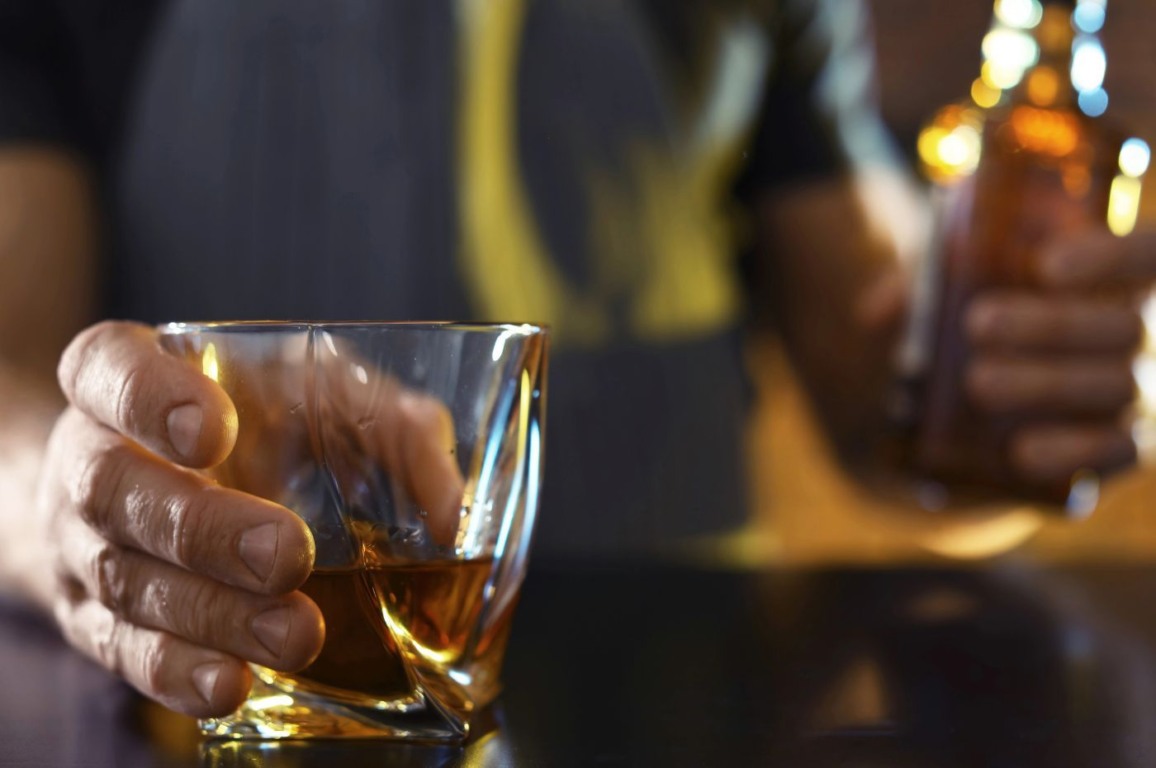 Homem segura copo com bebida alcoólica; imagem relacionada à morte por intoxicação com metanol. Homem segura copo com bebida alcoólica; imagem relacionada à morte por intoxicação com metanol.