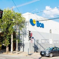 Fachada de uma unidade do Boa Supermercados em Jundiaí, com o logotipo azul e amarelo visível na lateral do prédio, árvores e carros estacionados na rua.
