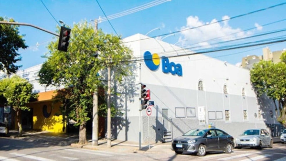 Fachada de uma unidade do Boa Supermercados em Jundiaí, com o logotipo azul e amarelo visível na lateral do prédio, árvores e carros estacionados na rua.
