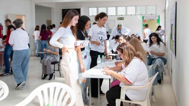 Grupo de pessoas realiza cadastro para doação de medula óssea em Jundiaí, com voluntários preenchendo formulários e recebendo orientações em sala organizada.