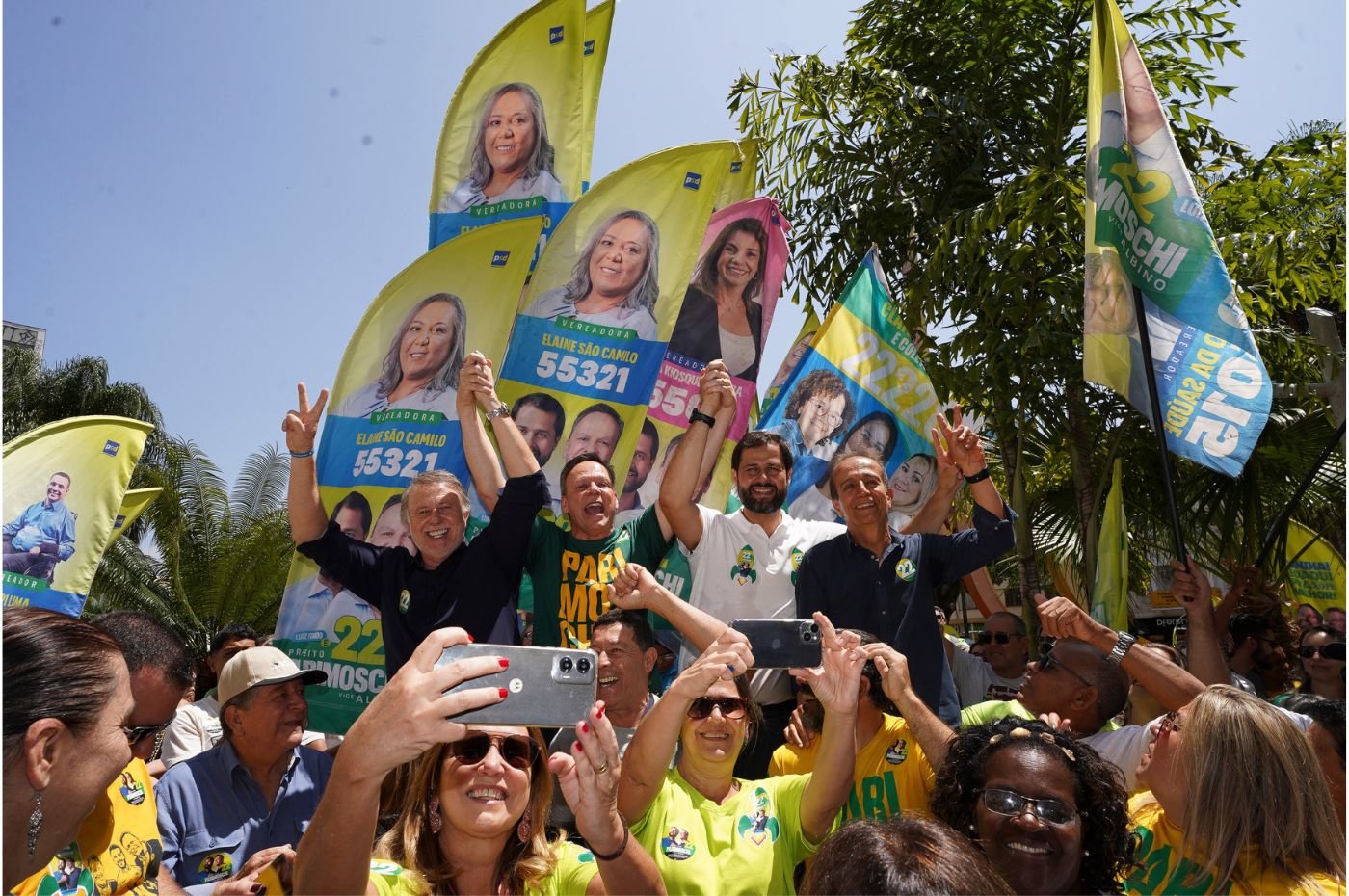 José Antonio Parimoschi e apoiadores comemoram em evento de campanha com bandeiras e cartazes de candidatos a vereador em Jundiaí.