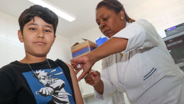 Profissional de saúde aplica vacina no braço de um menino durante a Campanha de Multivacinação em Jundiaí.