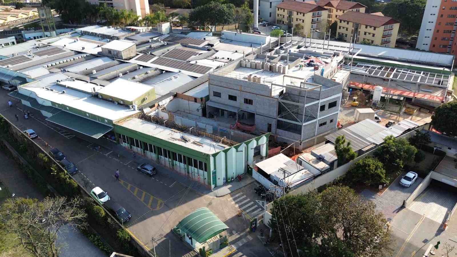 Vista aérea do Hospital Universitário de Jundiaí, com blocos hospitalares, área em obras e prédios residenciais ao fundo.