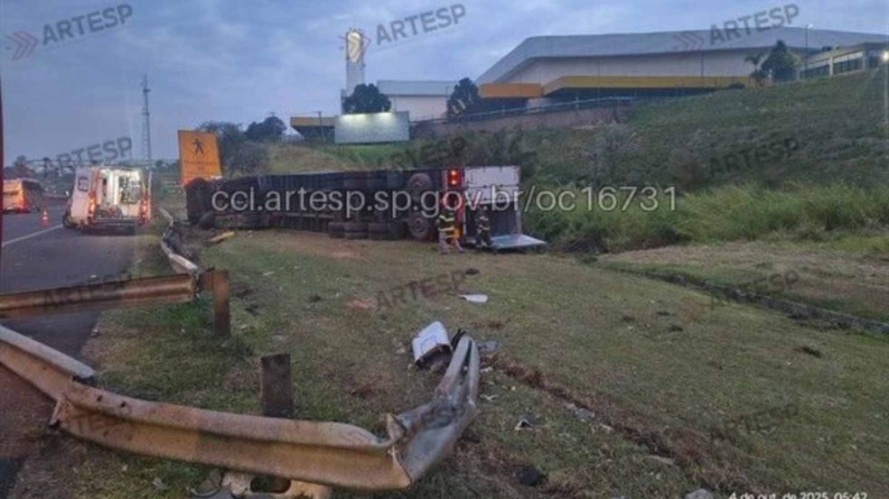 Carreta tombada no gramado lateral da Rodovia Anhanguera em Jundiaí, com viatura de resgate e agentes trabalhando na cena do acidente.