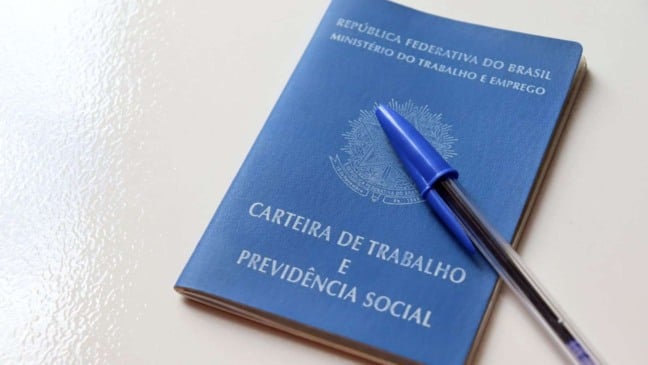 Carteira de Trabalho e Previdência Social azul com caneta esferográfica sobre a capa.
