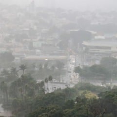 Vista aérea de Jundiaí sob forte chuva, com ruas molhadas, carros com faróis ligados e o prédio do Tauste visível ao fundo.