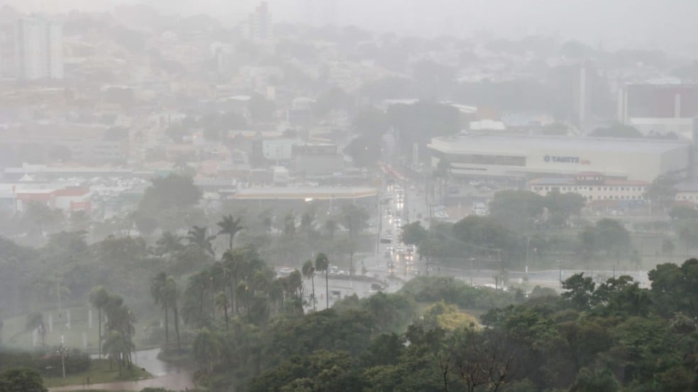 Vista aérea de Jundiaí sob forte chuva, com ruas molhadas, carros com faróis ligados e o prédio do Tauste visível ao fundo. Vista aérea de Jundiaí sob forte chuva, com ruas molhadas, carros com faróis ligados e o prédio do Tauste visível ao fundo.