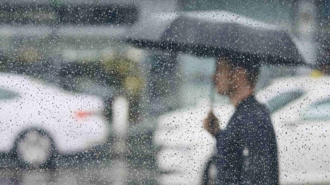 Pessoa caminha com guarda-chuva sob chuva em Jundiaí, vista através de janela com gotas de água. Pessoa caminha com guarda-chuva sob chuva em Jundiaí, vista através de janela com gotas de água.