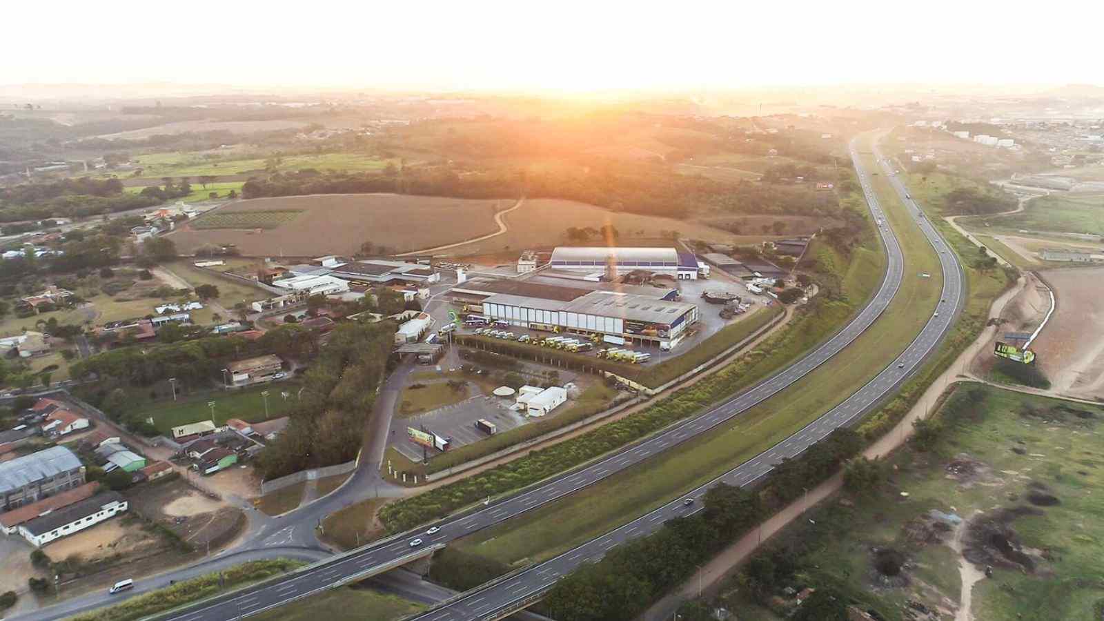 Vista aérea da De Marchi Indústria em Jundiaí, ao lado da rodovia, durante o pôr do sol.