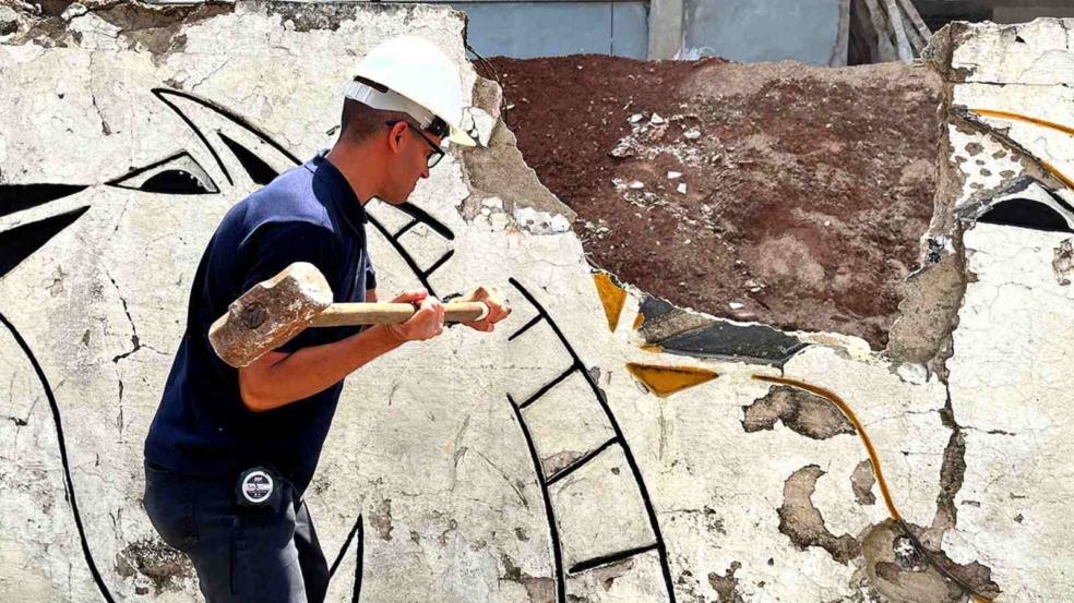 Homem com capacete branco derruba muro com marreta durante obra do novo Hospital Municipal de Várzea Paulista.