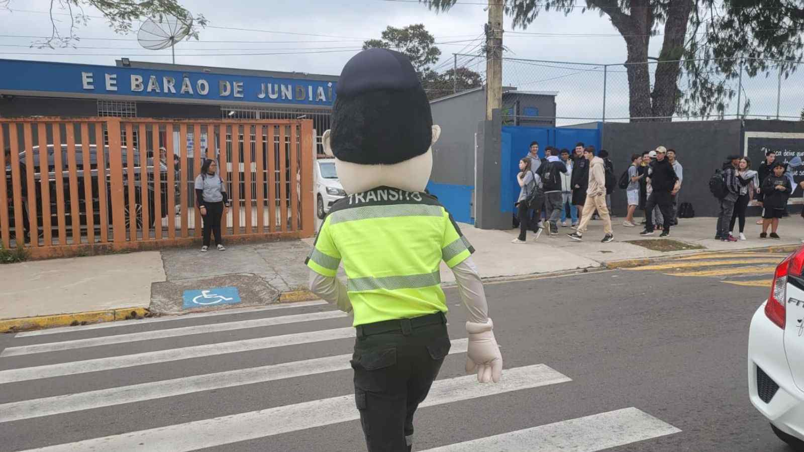 Mascote de trânsito atravessa faixa de pedestres em frente à Escola Barão de Jundiaí durante ação educativa da Semana Nacional do Trânsito.