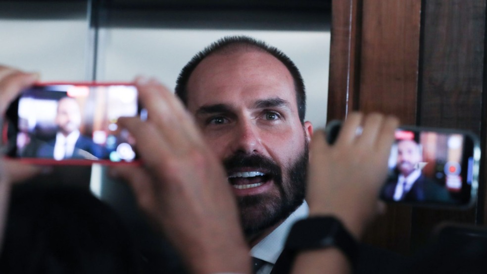 Deputado Eduardo Bolsonaro fala com a imprensa, cercado por celulares que gravam sua declaração. Deputado Eduardo Bolsonaro fala com a imprensa, cercado por celulares que gravam sua declaração.